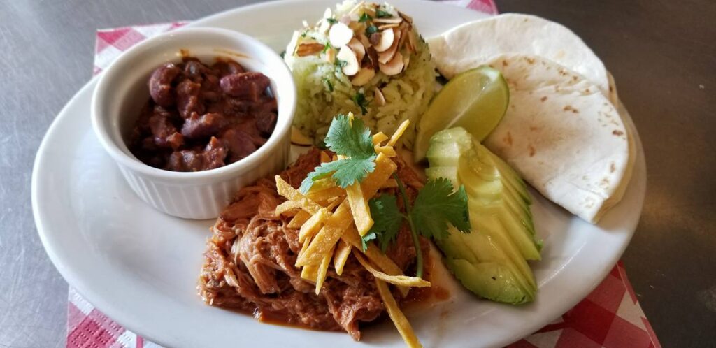 Taco makings on a plate, including tortillas, avocado, beans, and cheese.